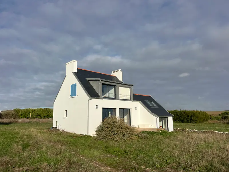Maison blanche aux volets bleus sous un ciel du Finistère